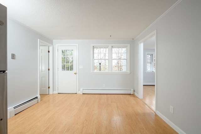 unfurnished room with a healthy amount of sunlight, light hardwood / wood-style flooring, and a baseboard heating unit