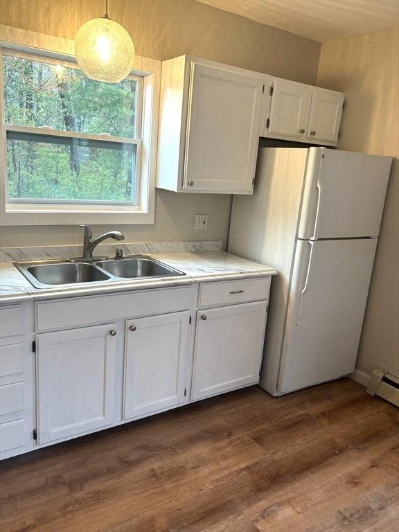kitchen featuring a sink, freestanding refrigerator, white cabinetry, light countertops, and dark wood finished floors