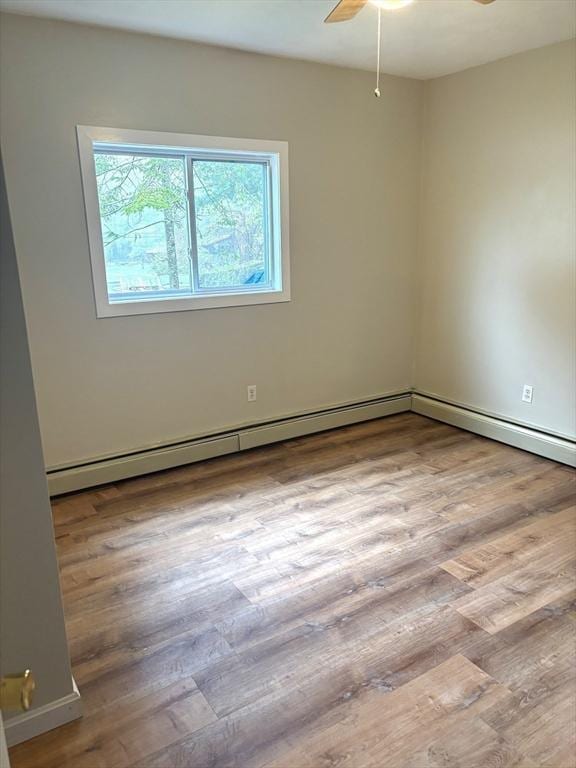 unfurnished room with ceiling fan, wood finished floors, and a baseboard heating unit