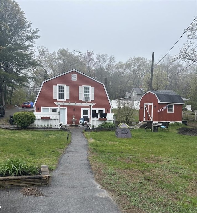 view of front of house featuring a gambrel roof, a shed, an outbuilding, and a front yard