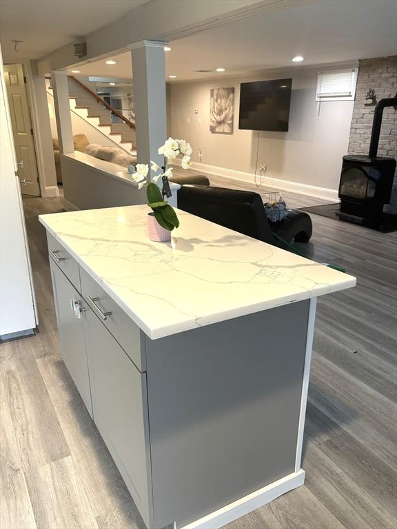 kitchen featuring a wood stove, light wood-type flooring, open floor plan, light stone counters, and recessed lighting