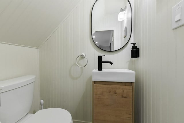 half bath with lofted ceiling, vanity, and toilet