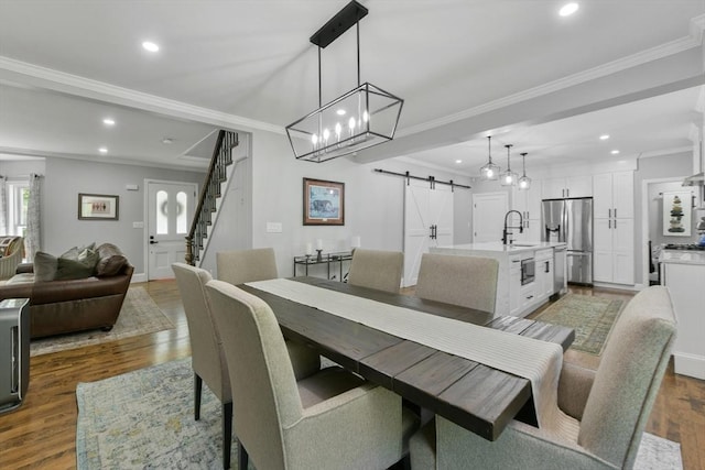 dining space with a barn door, stairway, dark wood-type flooring, crown molding, and recessed lighting