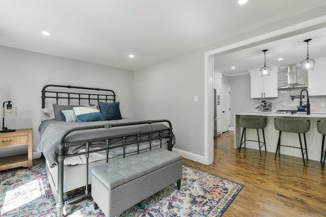 bedroom with baseboards, wood finished floors, and recessed lighting