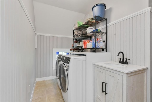 laundry area with laundry area, baseboards, washer and dryer, a sink, and light tile patterned flooring