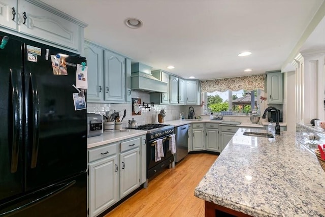 3 Centre St, Waltham, MA 02453 - kitchen featuring black appliances, premium range hood, a sink, tasteful backsplash, and light wood-style floors