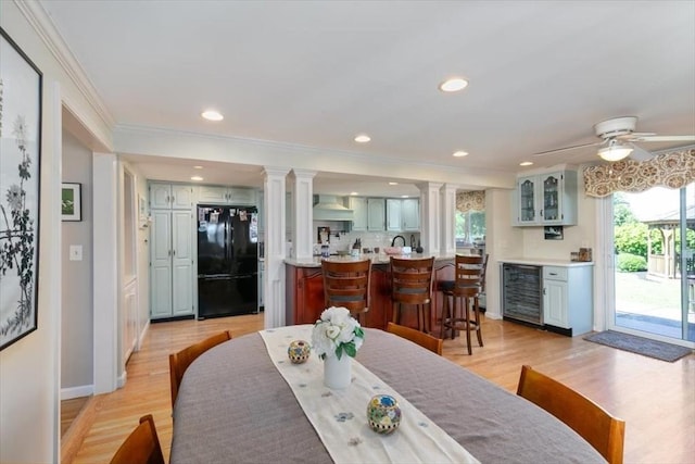 3 Centre St, Waltham, MA 02453 - dining room featuring wine cooler, crown molding, light wood-style flooring, bar, and ornate columns