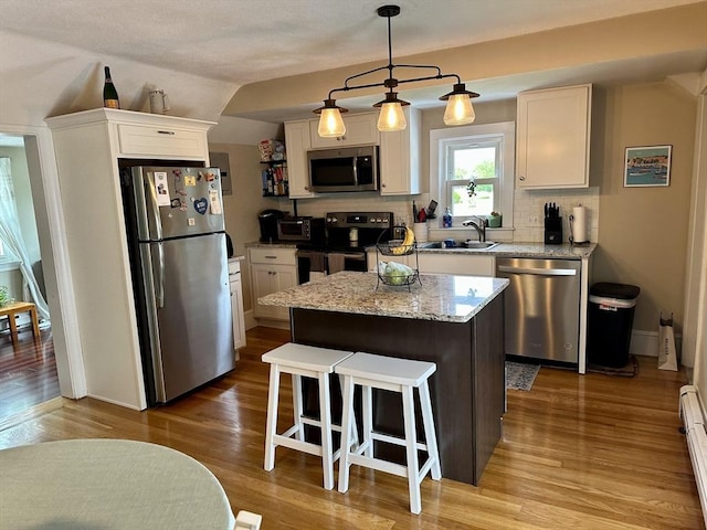 3 Centre St, Waltham, MA 02453 - kitchen with appliances with stainless steel finishes, a sink, white cabinetry, wood finished floors, and a kitchen island