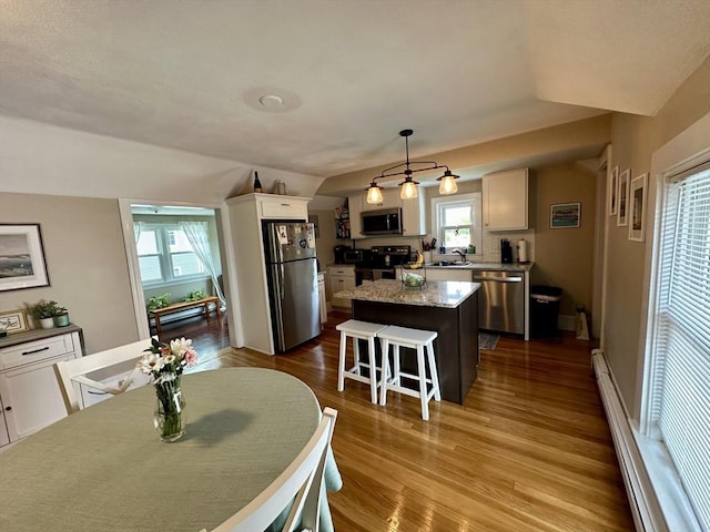 3 Centre St, Waltham, MA 02453 - kitchen with stainless steel appliances, a sink, a center island, dark wood finished floors, and a kitchen bar