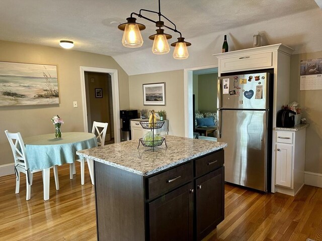 3 Centre St, Waltham, MA 02453 - kitchen featuring freestanding refrigerator, white cabinets, light wood-type flooring, lofted ceiling, and light stone counters