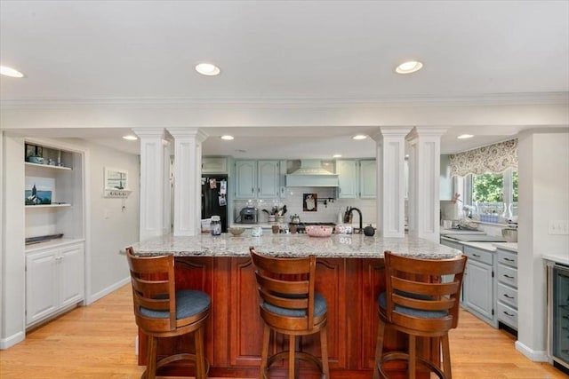 3 Centre St, Waltham, MA 02453 - kitchen with ornate columns, premium range hood, light wood-type flooring, a breakfast bar area, and recessed lighting