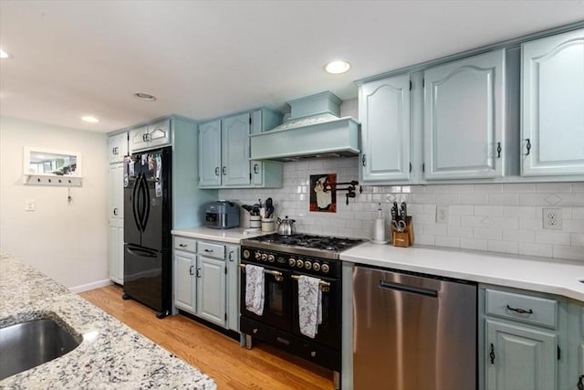 3 Centre St, Waltham, MA 02453 - kitchen featuring black appliances, custom exhaust hood, light wood finished floors, decorative backsplash, and recessed lighting