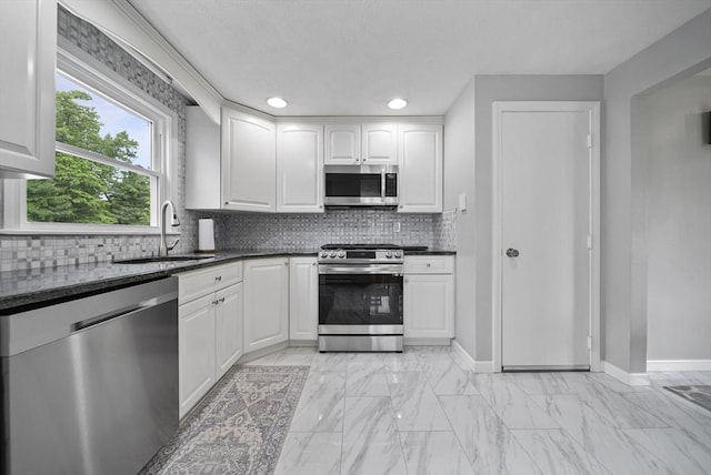 54 Forest St, Wilmington, MA 01887 - kitchen with appliances with stainless steel finishes, a sink, white cabinets, light marble finish floors, and backsplash