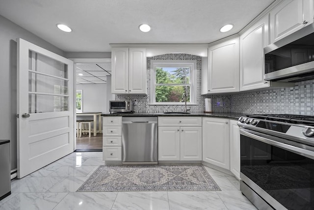 54 Forest St, Wilmington, MA 01887 - kitchen featuring stainless steel appliances, a sink, healthy amount of natural light, light marble finish flooring, and recessed lighting