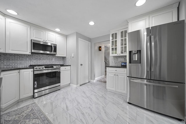 54 Forest St, Wilmington, MA 01887 - kitchen with appliances with stainless steel finishes, baseboards, glass insert cabinets, white cabinetry, and tasteful backsplash