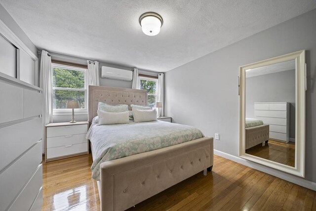 54 Forest St, Wilmington, MA 01887 - bedroom featuring a wall mounted AC, wood-type flooring, a textured ceiling, and baseboards