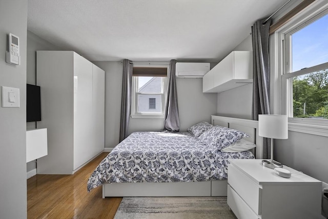 54 Forest St, Wilmington, MA 01887 - bedroom featuring multiple windows, light wood-style floors, an AC wall unit, and baseboards