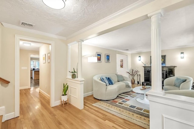 10 Ballard Ter, Lexington, MA 02420 - living room with ornate columns, light wood-type flooring, baseboards, crown molding, and a textured ceiling