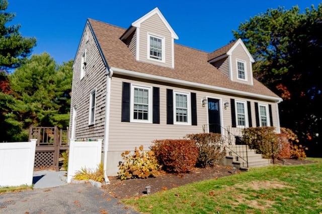 cape cod-style house with roof with shingles and fence