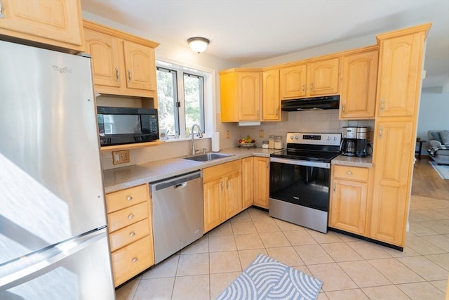 kitchen with under cabinet range hood, stainless steel appliances, light brown cabinetry, and a sink