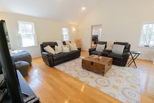 living area with baseboards, light wood-type flooring, and high vaulted ceiling