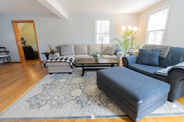 living area with beam ceiling and wood finished floors