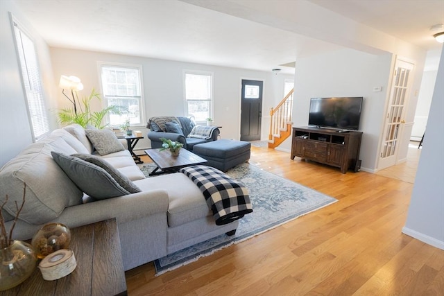 living area featuring stairway, light wood-style floors, and baseboards