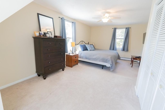 bedroom featuring baseboards, light colored carpet, a closet, a ceiling fan, and a baseboard radiator