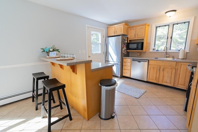 kitchen with a breakfast bar area, light tile patterned floors, light brown cabinets, a sink, and stainless steel appliances