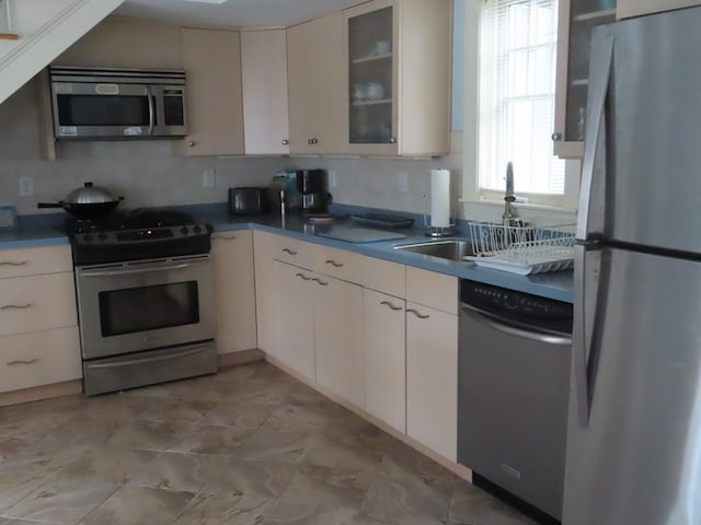 kitchen featuring backsplash, appliances with stainless steel finishes, and light tile patterned floors