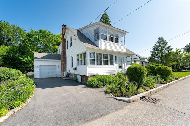 23 Shawmut Ave, Lowell, MA 01851 - view of front of home featuring a chimney, an outbuilding, asphalt driveway, a detached garage, and roof with shingles
