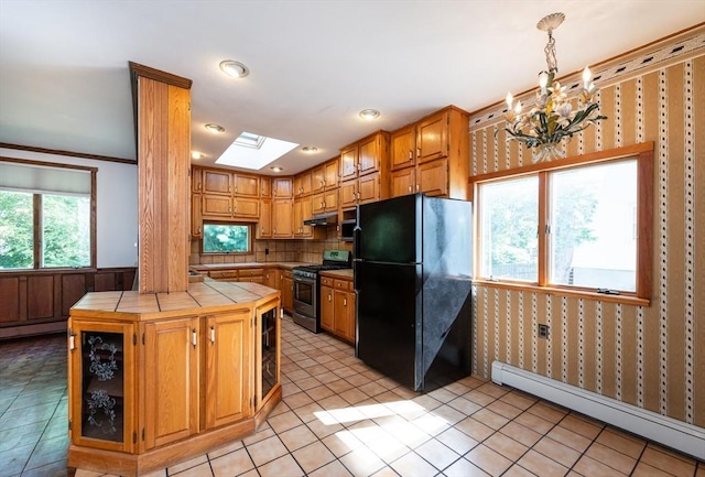 23 Shawmut Ave, Lowell, MA 01851 - kitchen featuring stainless steel range with gas stovetop, tile counters, freestanding refrigerator, baseboard heating, and a skylight