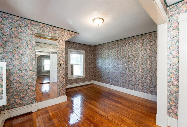 23 Shawmut Ave, Lowell, MA 01851 - unfurnished dining area with baseboard heating, hardwood / wood-style floors, baseboards, wallpapered walls, and a textured ceiling