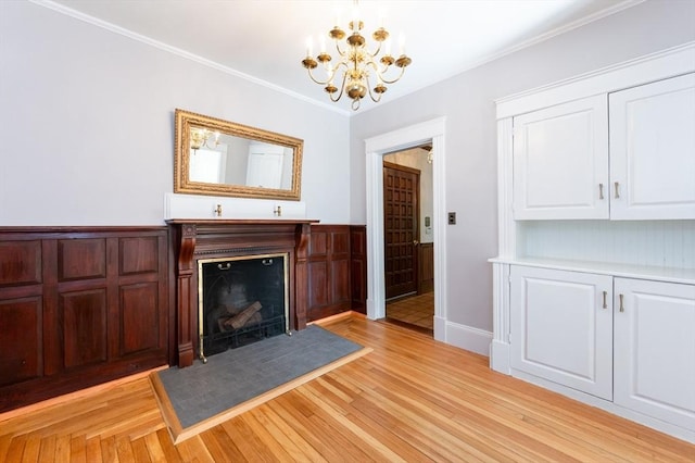 23 Shawmut Ave, Lowell, MA 01851 - unfurnished living room with a chandelier, a fireplace, light wood finished floors, crown molding, and wainscoting
