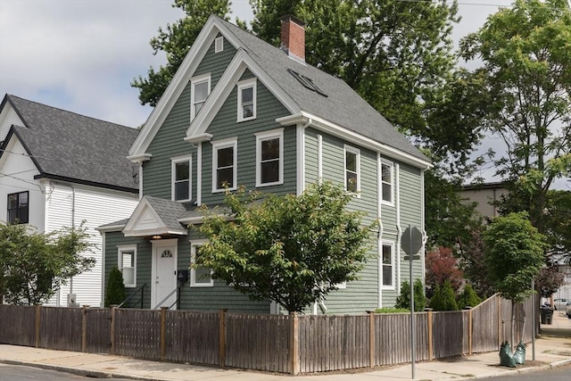 27 Round Hill St, Boston, MA 02130 - view of front of home featuring a fenced front yard, roof with shingles, and a chimney