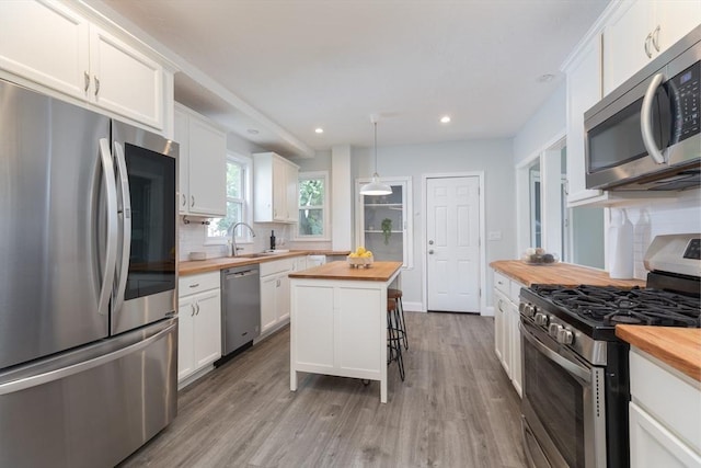 27 Round Hill St, Boston, MA 02130 - kitchen featuring butcher block counters, stainless steel appliances, decorative backsplash, white cabinetry, and recessed lighting