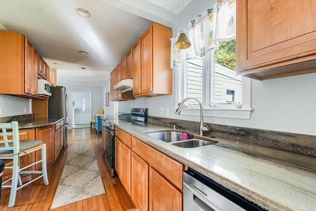 kitchen featuring stainless steel appliances, wood-type flooring, sink, and pendant lighting