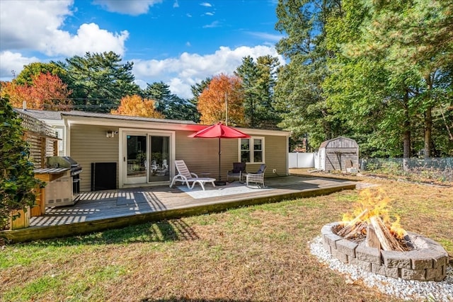 back of house with a storage shed, a fire pit, and a wooden deck