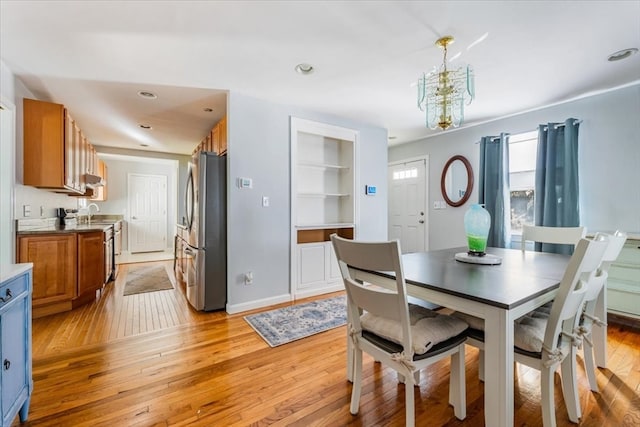 dining room with an inviting chandelier, light hardwood / wood-style flooring, and built in shelves