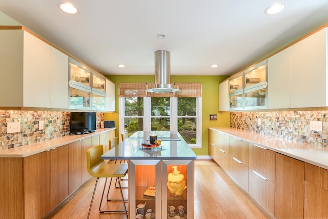 kitchen with light hardwood / wood-style flooring, white cabinetry, a kitchen island, and a breakfast bar area