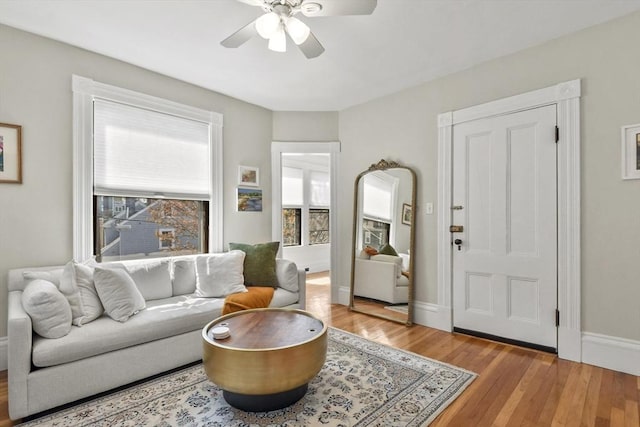 living area with baseboards, a ceiling fan, and wood finished floors