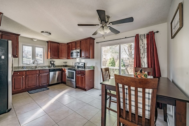 kitchen with stainless steel appliances, a wealth of natural light, and light stone countertops