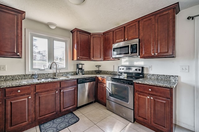 kitchen featuring sink, appliances with stainless steel finishes, a textured ceiling, and light tile patterned floors