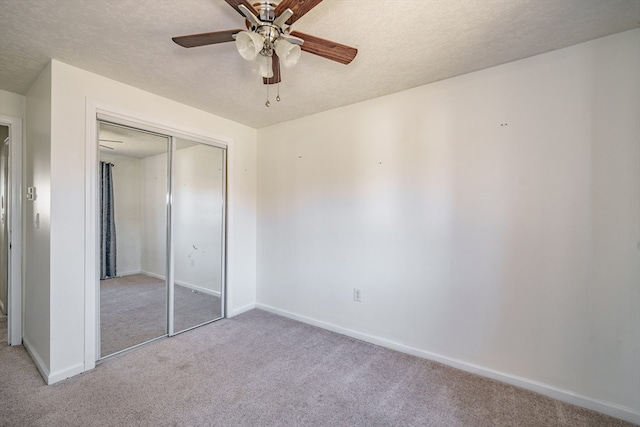 unfurnished bedroom with ceiling fan, light carpet, a closet, and a textured ceiling