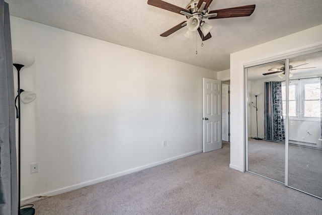 unfurnished bedroom featuring a closet, a textured ceiling, light carpet, and ceiling fan