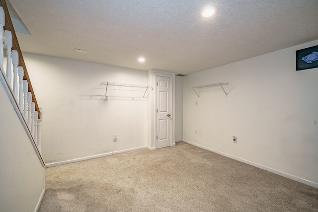 basement with a textured ceiling and light carpet