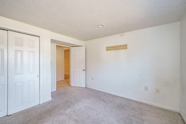 unfurnished bedroom featuring a closet, a textured ceiling, and light colored carpet