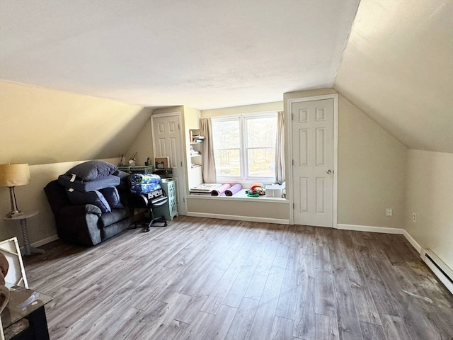 additional living space featuring hardwood / wood-style floors, a baseboard heating unit, and lofted ceiling