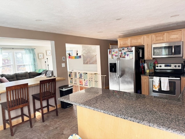 kitchen featuring light brown cabinetry, a textured ceiling, and stainless steel appliances