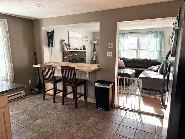 bar with refrigerator, a brick fireplace, a textured ceiling, baseboard heating, and butcher block countertops